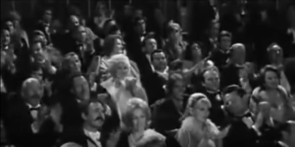 Black and white image of a theater crowd in formal attire